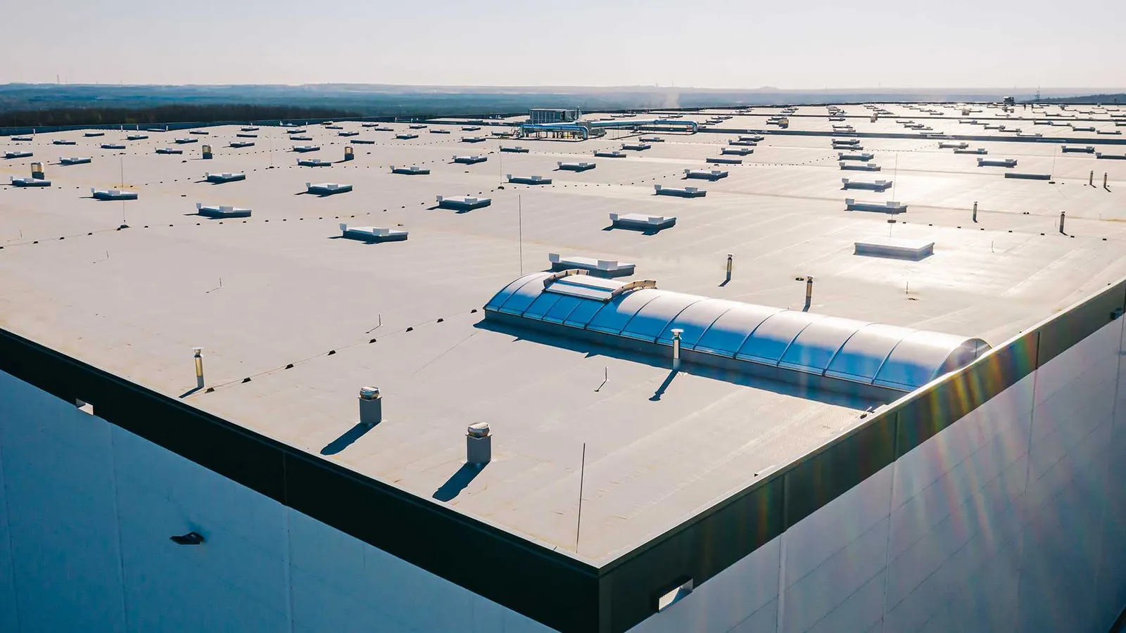 Large commercial flat roof with rooftop equipment and skylights